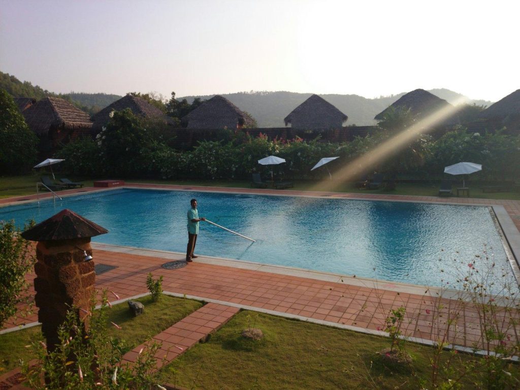 Pool technician cleaning a large pool at sunrise